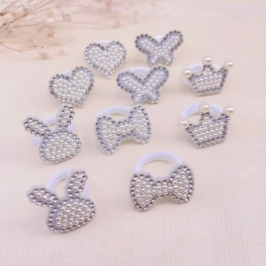 Détail d'un lot d'élastiques à perles et strass avec motifs de cœur et de nœud papillon