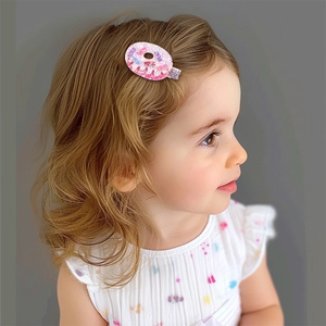 Gros plan d'une pince à cheveux beignet pailletée rose portée par une enfant
