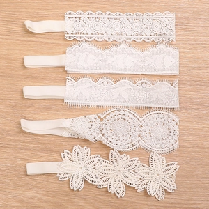 5-pack baby white lace floral headbands with elastic bands on light wood background