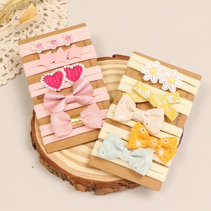Détail des bandeaux à broderie florale et nœuds sur fond de bois naturel et dentelle