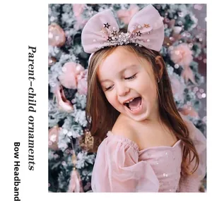 Détail d'un serre-tête nœud en tulle rose avec étoiles dorées et perles de fête
