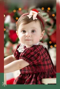 Close-up of a baby wearing a red Christmas headband with Santa Claus fabric ornament