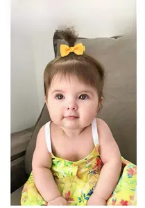 Close-up of a bright yellow grosgrain bow hair clip on a baby's head with a soft background