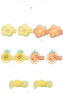 Detail of embroidered fabric hair clips featuring pineapple, carrot and flower designs