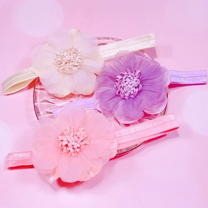 Détail de trois bandeaux élastiques pour bébé avec de grandes fleurs en organza