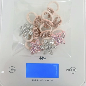 Detail view of pink and white elastic hair ties with rhinestone animal charms on a scale