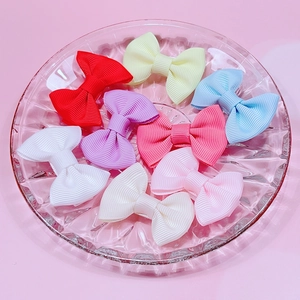 Lot de 8 barrettes à nœuds colorées pour bébé sur plateau en verre et fond rose