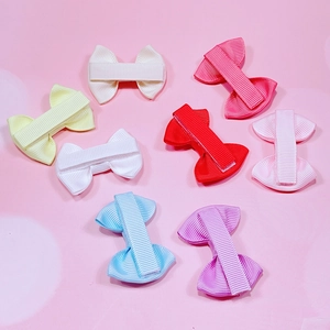 Détail d'un lot de barrettes à nœuds colorés pour bébés sur fond rose poudré
