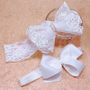 Detail of baby white lace bow headbands with faux pearls and rhinestones on a glass tray
