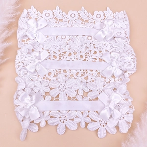 Detailed view of three white lace baby headbands with satin bows on a soft pink background