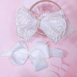 Detail view of white lace baby headbands with delicate faux pearl and embroidery details