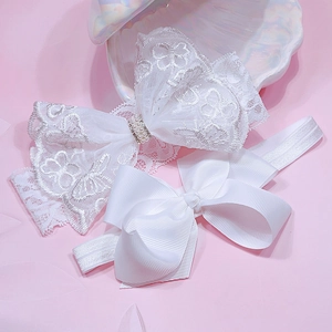 Close-up of white lace bow headband with pearl details on a soft pink background
