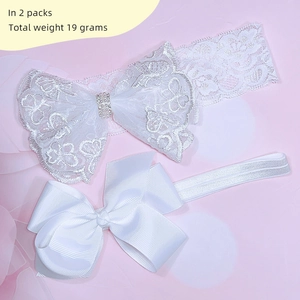 Detail of two white lace and satin baby headbands with embroidery and bows