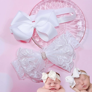 Detail view of white lace and grosgrain baby headbands with pearl and bow accents