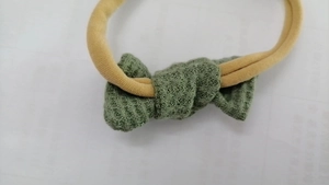 Close-up of baby waffle fabric headband with green bow and soft yellow nylon strap