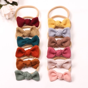 Flat lay showing 12 colors of soft waffle knit bow headbands for baby girls