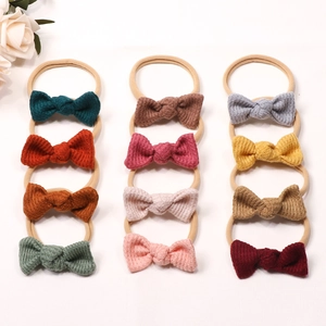 Flat lay of 12 multi-colored waffle fabric bow headbands with soft nylon elastic bands