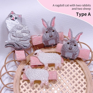 Detail showing 5-piece set of embroidered animal hair clips with pink glitter fabric base