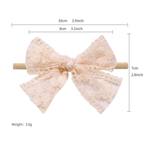 Beige lace baby headband with bow and daisy floral detail on a soft elastic band