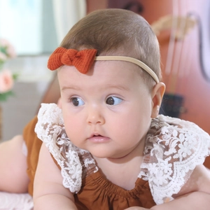 Close-up of baby waffle headbands with orange bow and white delicate lace collar details