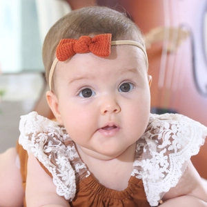 Detailed texture of burnt orange waffle knit bow headband on a baby's head