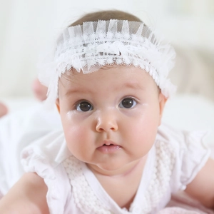 Gros plan sur un bandeau de baptême en dentelle blanche avec broderies de fleurs