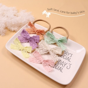 Detailed macro view of six candy-colored lace bow headbands in a white tray for infants