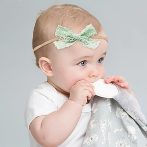 Detail of baby nylon headband featuring a mint green hollow lace bow on an infant model