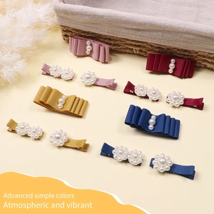 Close-up of handmade ribbon bow hair clips with pearls in pink, red, and navy colors