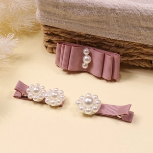 Detail view of handmade pink ribbon bow hair clips with elegant pearl embellishments
