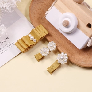 Detailed view of three handmade ginger yellow bow hair clips with pearls and ribbons