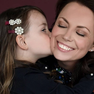 Close-up of pearl flower hair clips on a young girl showing dark red satin details