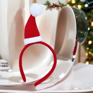 Détail d'un serre-tête bonnet de Noël rouge avec pompons blancs sur support céramique