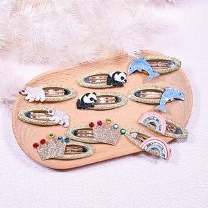 Detail of embroidered cartoon animal hair clips with glitter finish on a wooden tray