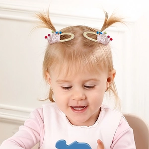 Close-up of a child wearing a pink glitter crown hair clip with colorful beads and gold trim