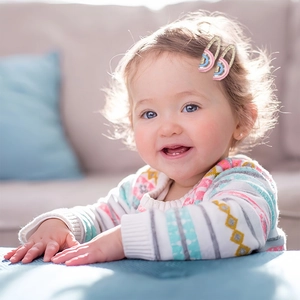 Detail of pink and blue glitter rainbow hair clip on a smiling young girl