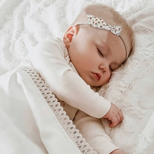 Baby cotton floral bow headband with soft seamless nylon band shown on sleeping infant
