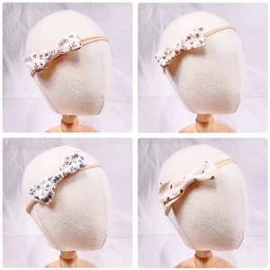 Detail view of four floral baby headbands with elastic nylon straps on a display model