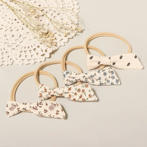Close-up of four floral cotton baby headbands with elastic nylon bands on a lace mat