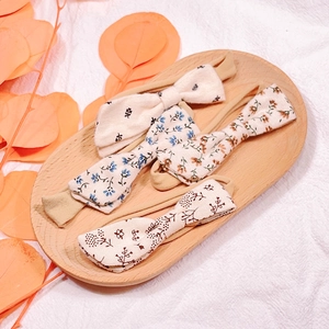 Detailed set of three floral cotton baby headbands with elastic nylon bands in a wooden tray