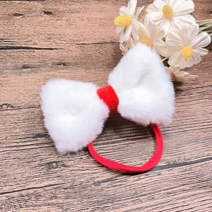 Detail of soft white faux fur bow hair tie with red velvet center and elastic band