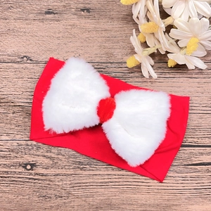 Detail of red baby headband with a large white faux fur bow on wooden background