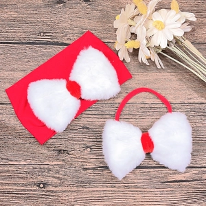 Close-up of red Christmas headbands with white faux fur bows on a dark wooden background