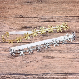 Detailed close-up of gold and silver snowflake elastic headbands on dark wood