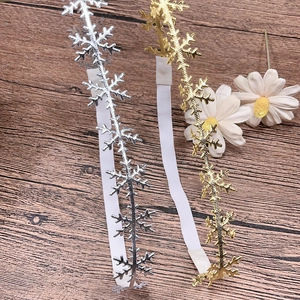 Detailed view of gold and silver hollow snowflake headbands on a wooden surface