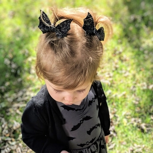 Close-up of glittery black bat wing hair clips worn by a child for Halloween parties