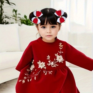 Détail de barrettes à nœuds rouge et blanc avec une robe de fête en velours pour fille