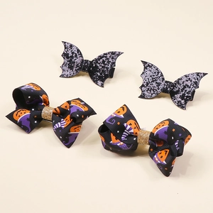 Detail view of Halloween glitter bat wing hair clips and pumpkin bow ribbon accessories