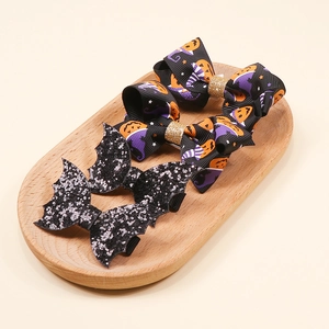 Detailed view of Halloween hair clips with pumpkin bows and bat wings in a tray