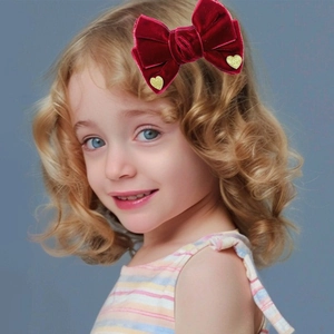 Detalle de un lazo para el pelo de terciopelo burdeos con clips de corazones dorados